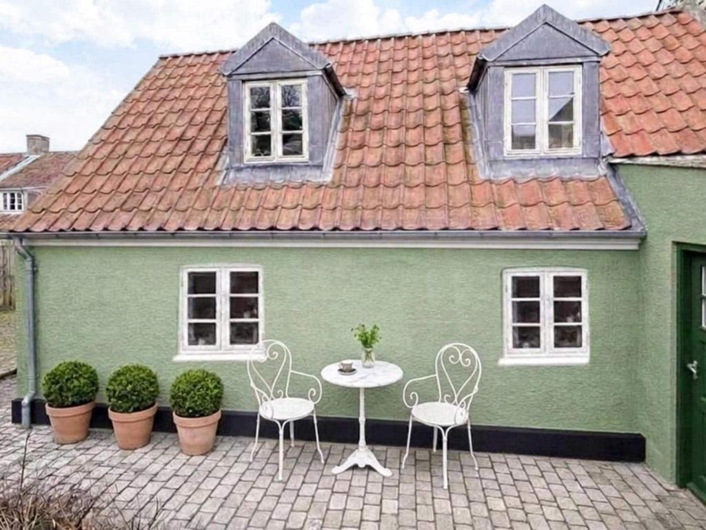 a green house with a table and chairs in front of it at 4 star holiday home in Ringkøbing in Ringkøbing