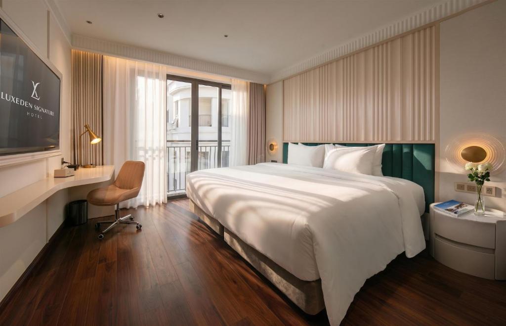 a hotel room with a large bed and a desk at Luxeden Classic Hotel in Hanoi