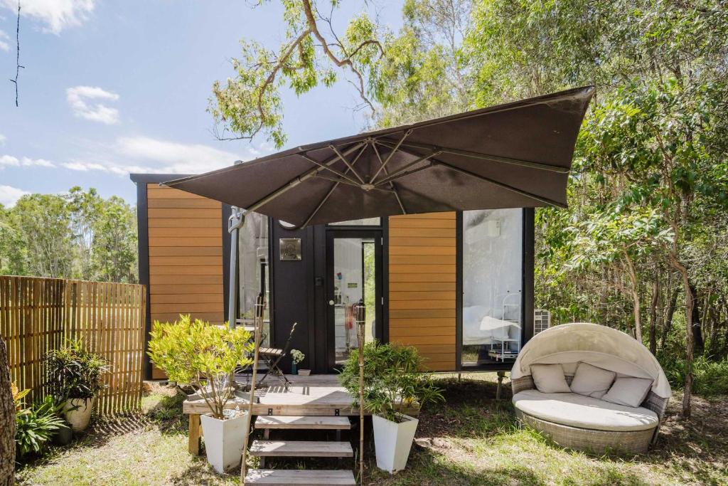 a small house with a couch and an umbrella at Clarence Farm Stay by Tiny Away in Maclean