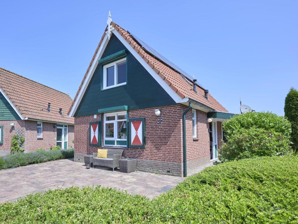 a house with a black roof and a patio at Poldergeluk in Ooltgensplaat