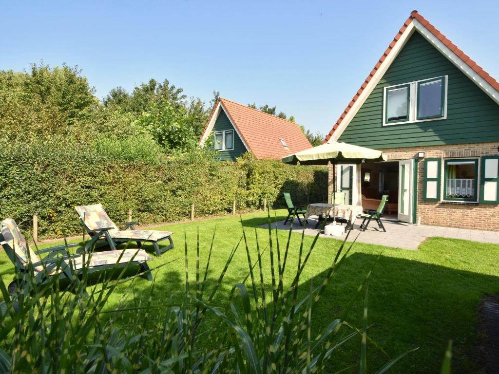 a house with a yard with chairs and an umbrella at Graspieper in Zonnemaire