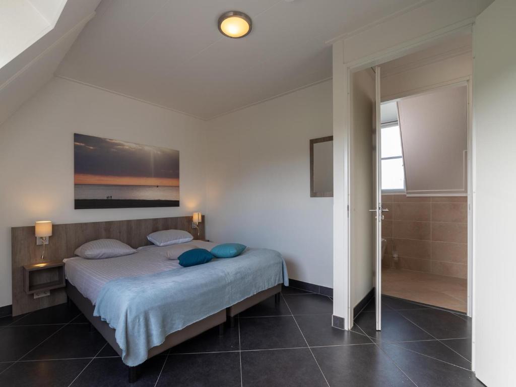 a bedroom with a bed with blue pillows at Zwembadvilla in Colijnsplaat