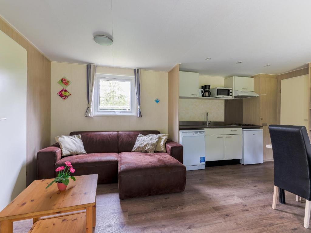ein Wohnzimmer mit Sofa und Tisch und eine Küche in der Unterkunft Easy Chalet in Vessem