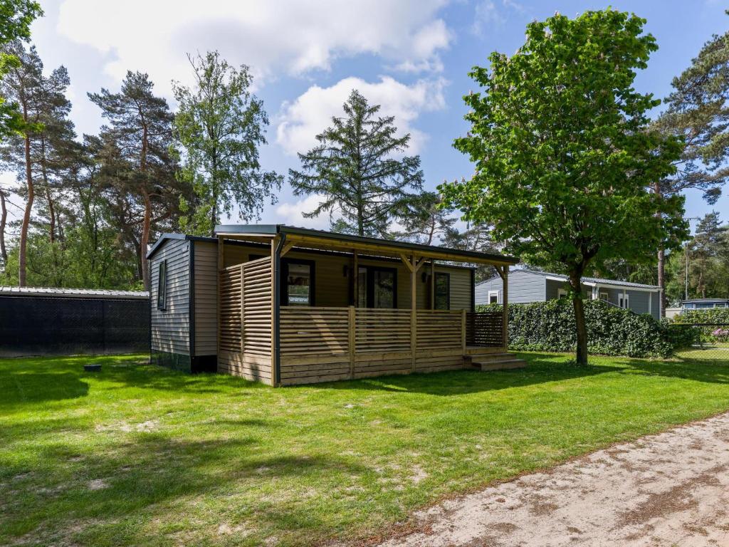 a tiny house in a yard with a tree at Boslodge in Vessem