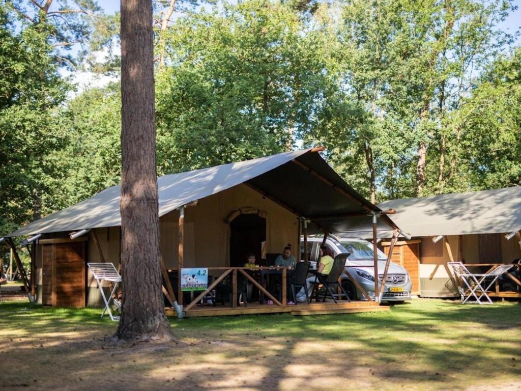 a tent with a man sitting at a table in front at Safaritent 4 in Vessem