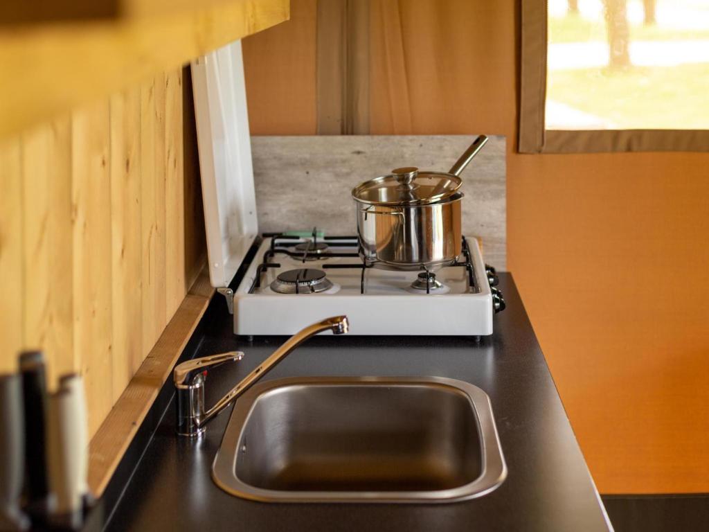 a kitchen counter with a sink and a pot on a stove at Safaritent 6 in Vessem