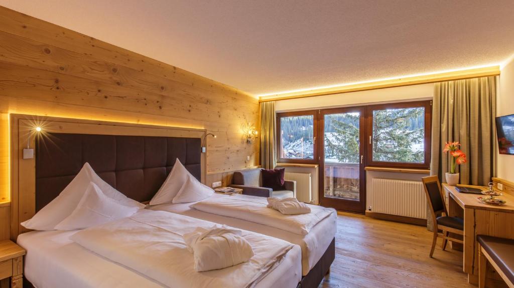 a hotel room with two beds and a desk and window at Hotel Plattenhof in Lech am Arlberg