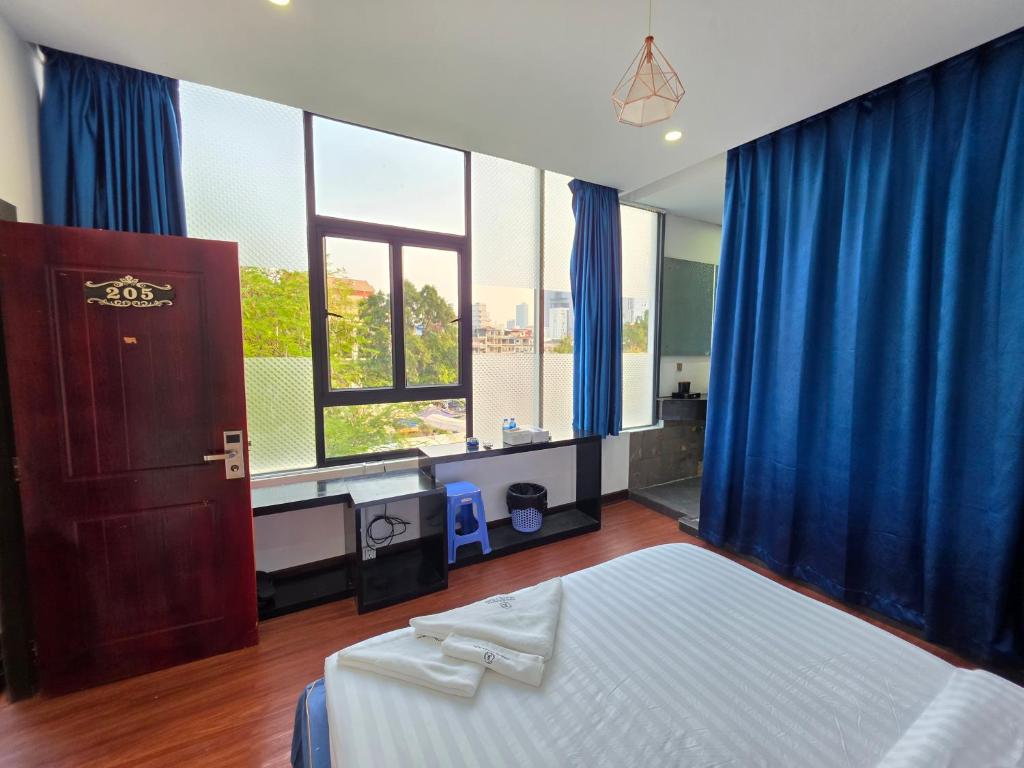 a bedroom with blue curtains and a bed and a window at Jason Residencia One Hotel in Phnom Penh
