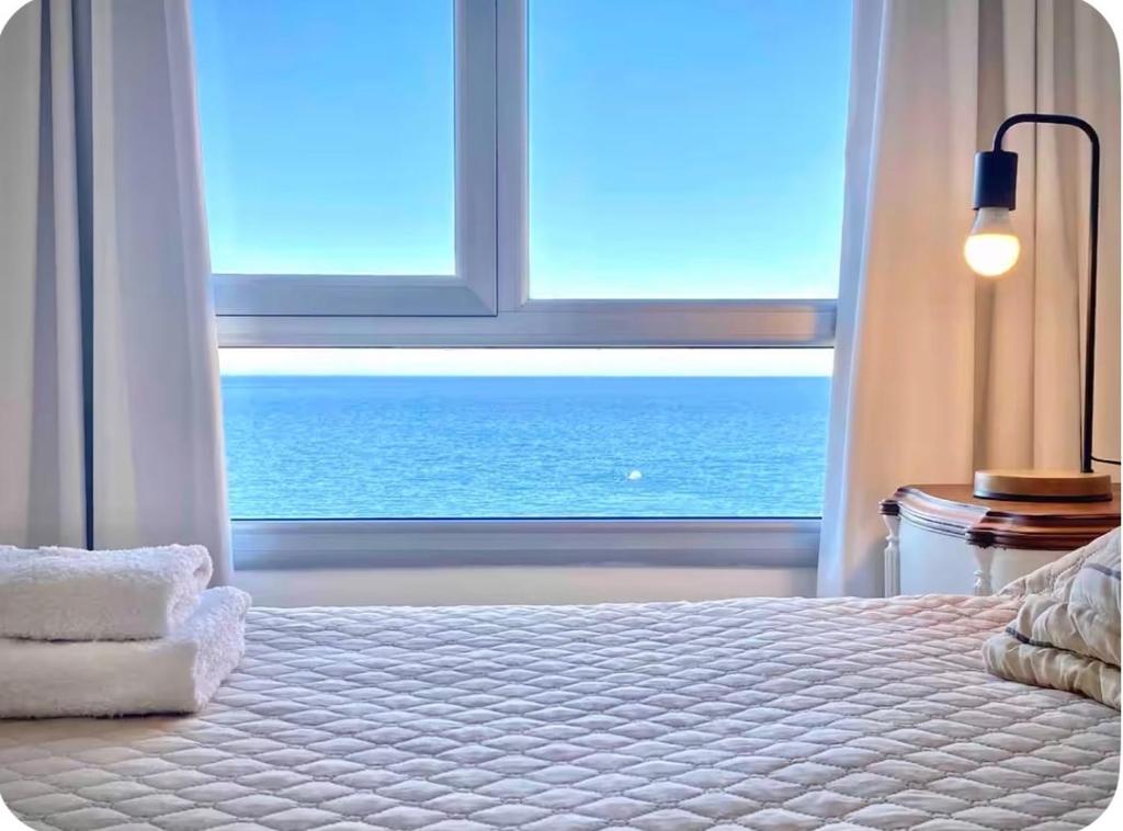 a bedroom with a large window overlooking the ocean at Bella Vista in Puerto Madryn