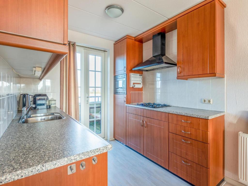 a kitchen with wooden cabinets and a sink at Schippershuis Stavoren in Stavoren