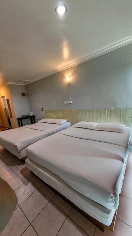 a room with three beds in a room with at Highway Inn in Mukah