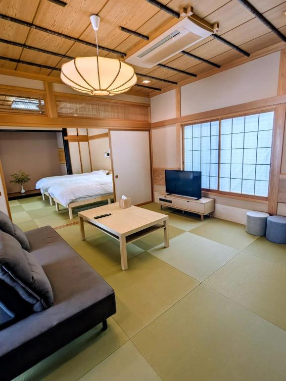 a living room with a couch and a bed and a tv at 和の貸切宿yanagiya in Daisen