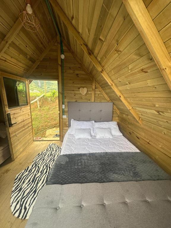 a bed in a wooden room with a zebra rug at Finca la Cabaña in Cisneros