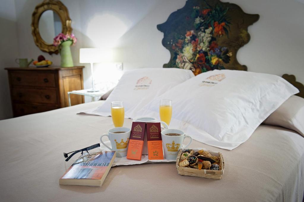 een bed met twee kopjes sinaasappelsap en een dienblad met eten bij Le Case Dello Zodiaco albergo diffuso in Modica