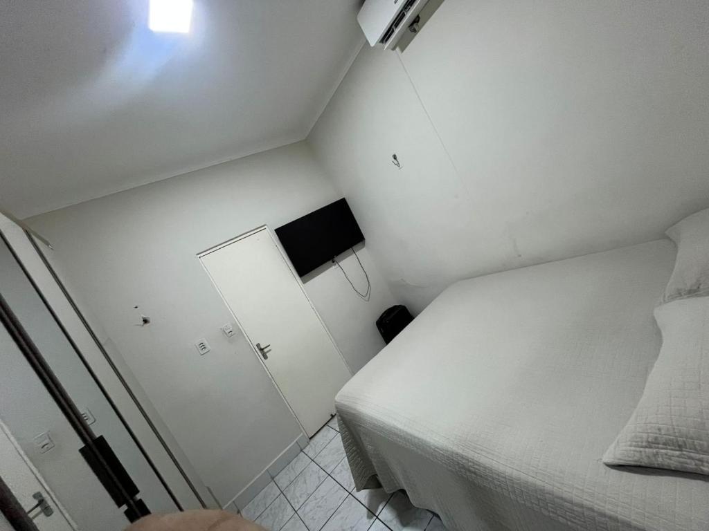 a small white bedroom with a bed and a small cabinet at Casa ampla e confortável in Mossoró