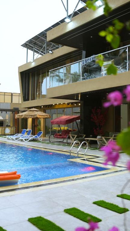 a building with a swimming pool with chairs and umbrellas at Bianca Villa in Al Rama