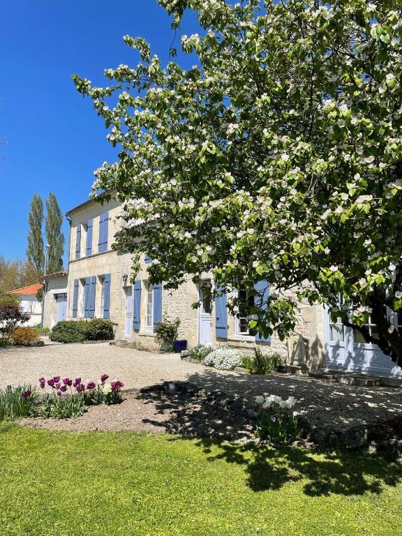 a house with a flowering tree in front of it at Le Clos du Plantis in Sonnac