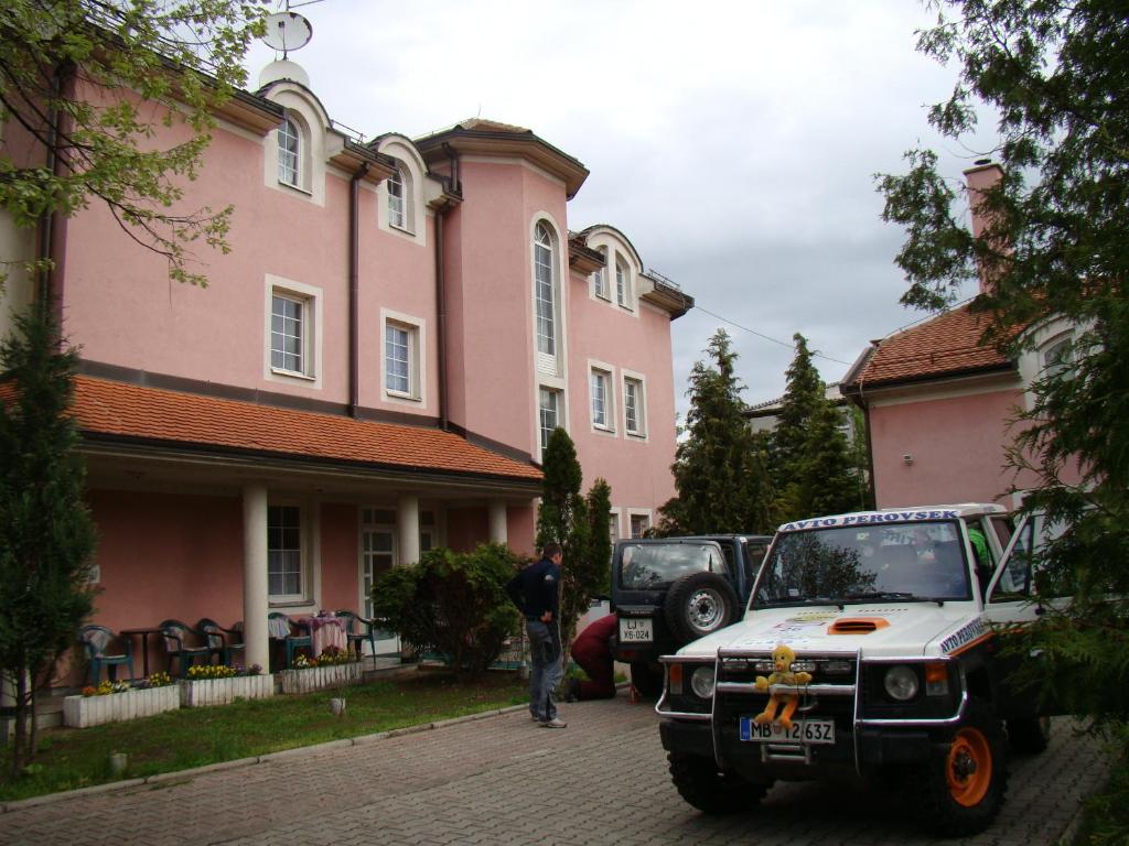 Un uomo in piedi di fronte a una casa rosa di Guest House Zamak a Banja Luka