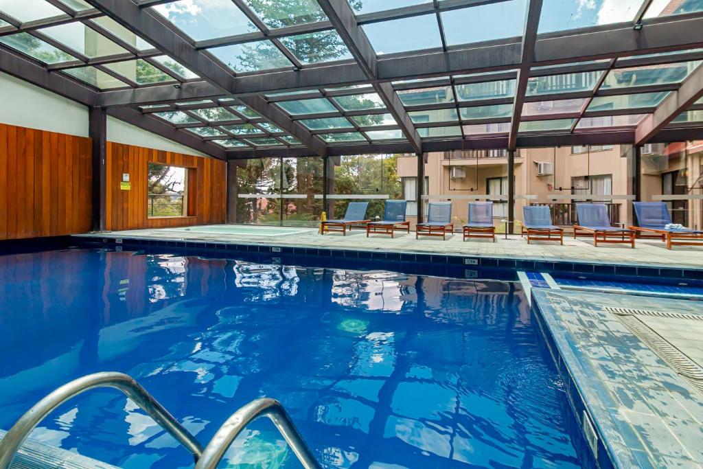 a swimming pool with chairs and a large glass ceiling at Flat Serrano com Total Acesso ao Wish Resort in Gramado