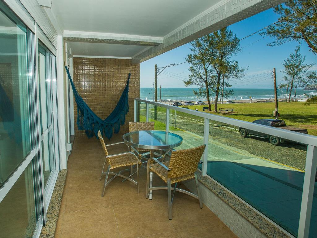 a balcony with a table and chairs and a view of the ocean at Residencial Villa Lobos in Torres