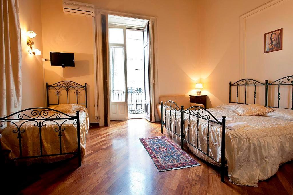 1 dormitorio con 2 camas y TV en la pared en B&B Alba, en Catania