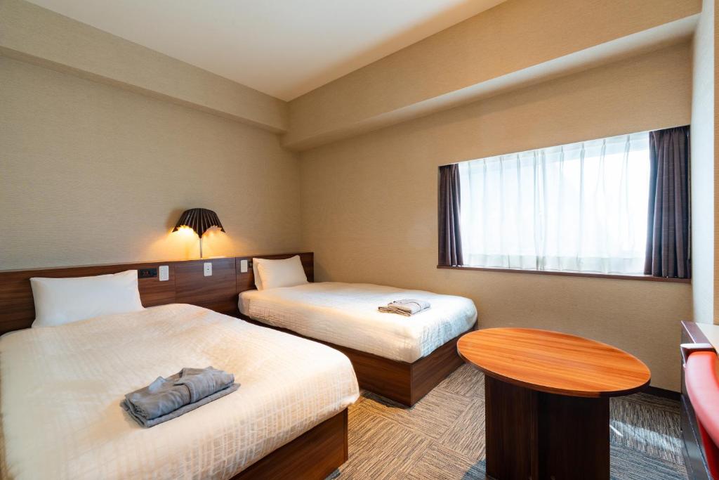 a hotel room with two beds and a table and a window at Koraku Garden Hotel Tokyo in Tokyo