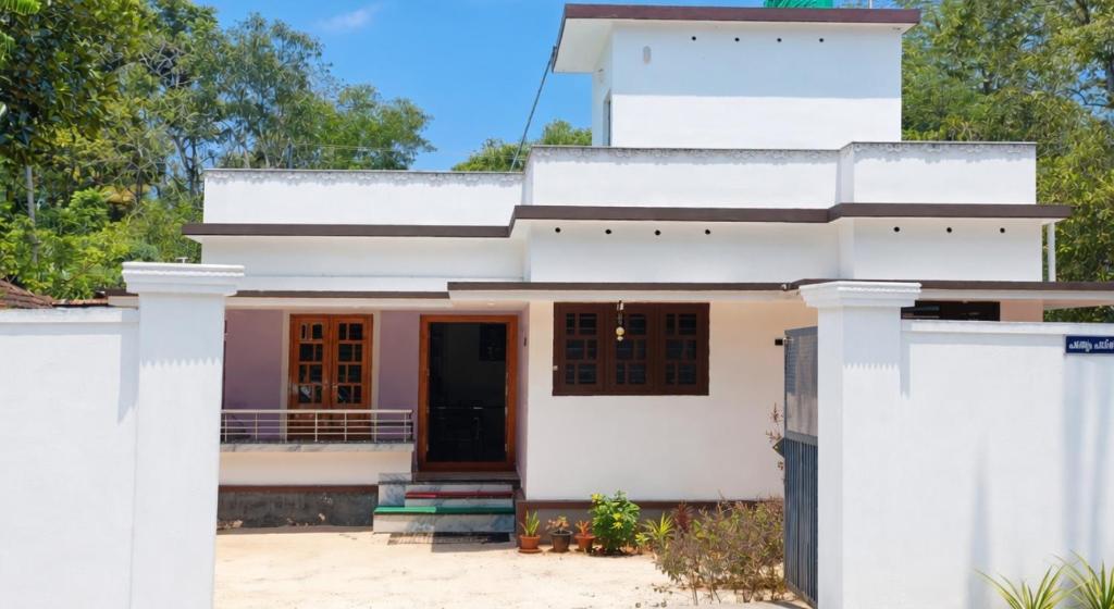 a white house with a black door at Leland Homestay in Mararikulam