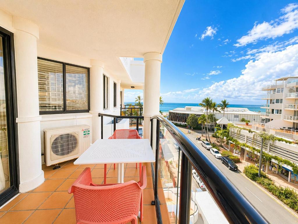 a balcony with a table and chairs and a view of the ocean at Stylish 1 Bedroom with Private Rooftop Spa at the Aegean in Mooloolaba