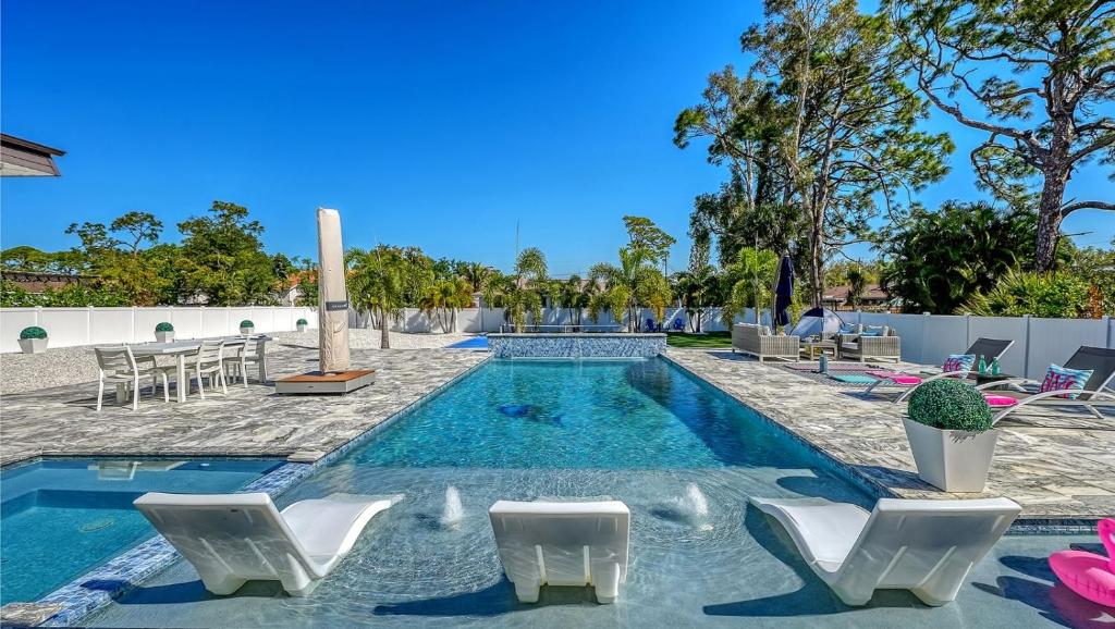 a swimming pool with white chairs and a swimming pool at Stay & Play Sarasota in Sarasota