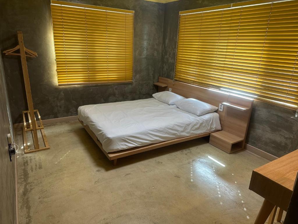 a bedroom with a bed with white sheets and windows at Osoha guest house in Samcheok