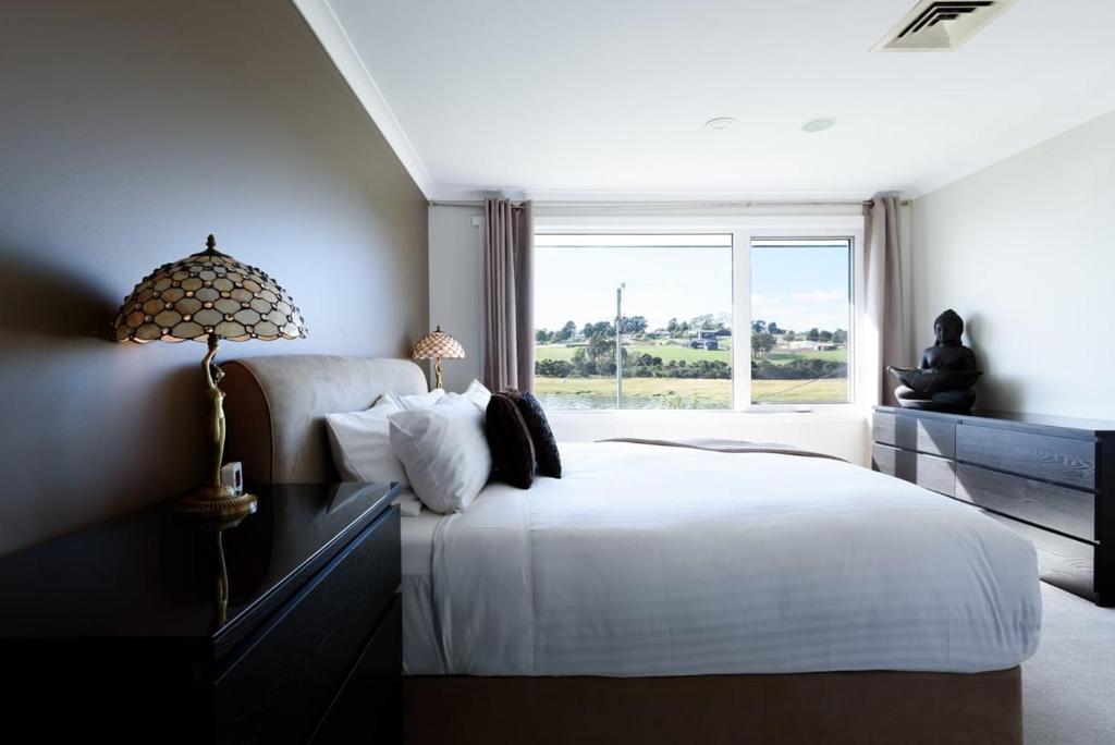 a bedroom with a white bed and a window at Tamar River Hideaway in Legana