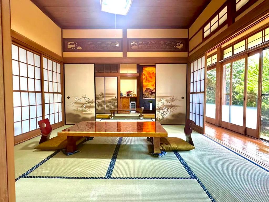 a room with a table and chairs and windows at 古民家松 in Isumi