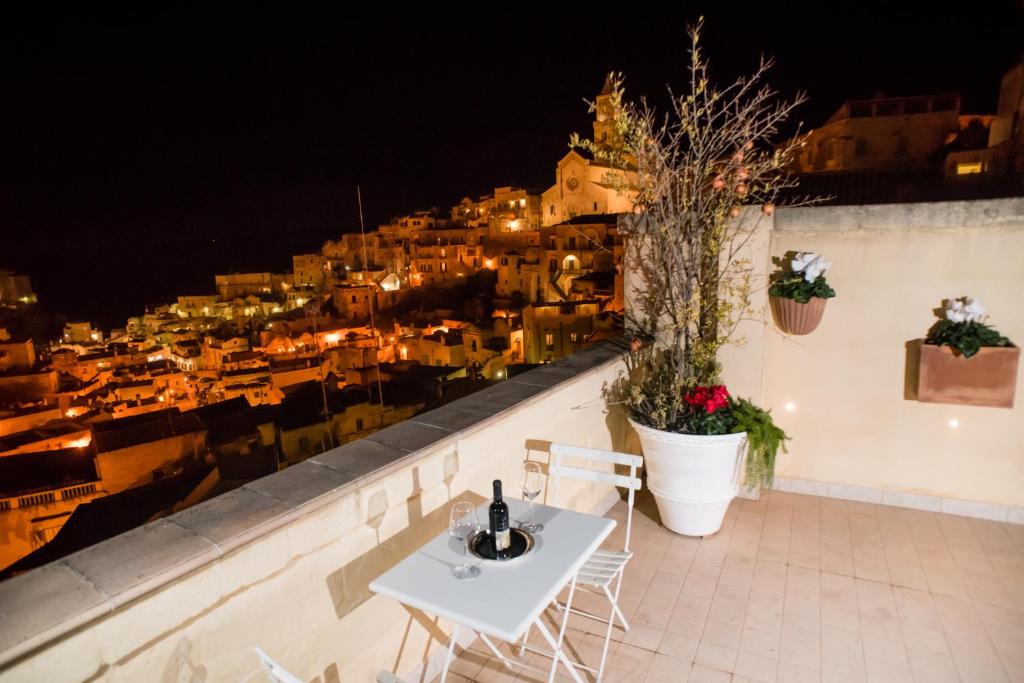 a table and chairs on a balcony with a view of a city at L'Incanto Luxury Rooms in Matera