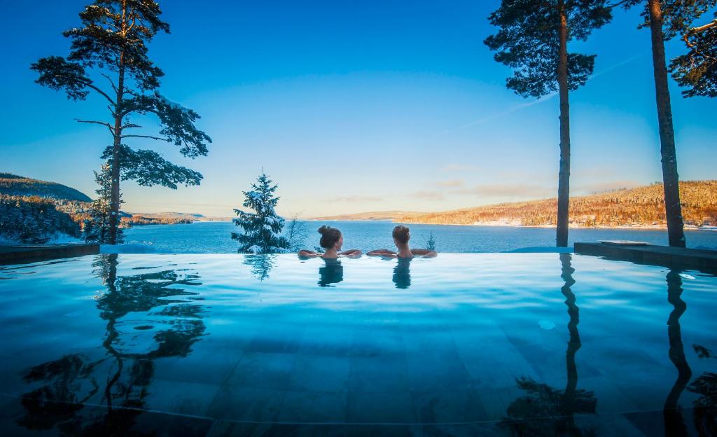 dos personas sentadas en el agua en una piscina infinita en Orbaden Spa & Resort, en Vallsta