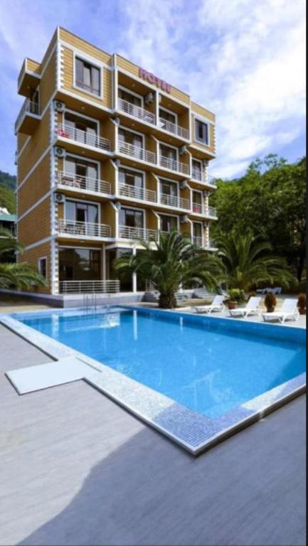 a hotel with a large swimming pool in front of a building at Medea Kvariati in Kvariati