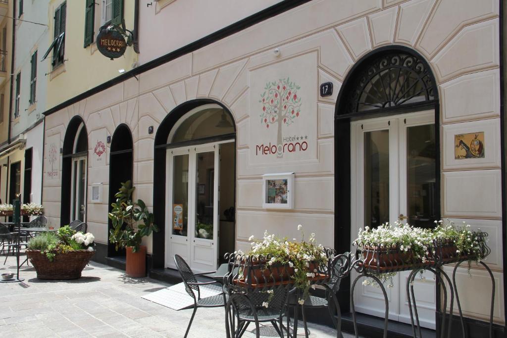 un café avec des tables, des chaises et des fleurs en pots dans l'établissement Hotel Melograno, à Spotorno