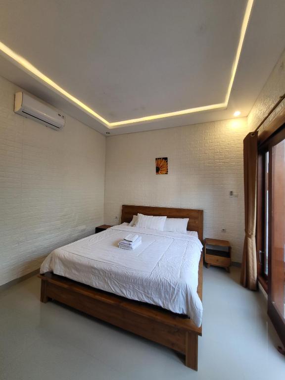 a bedroom with a large bed with white sheets at Pondok Ashanara Sading in Sempidi