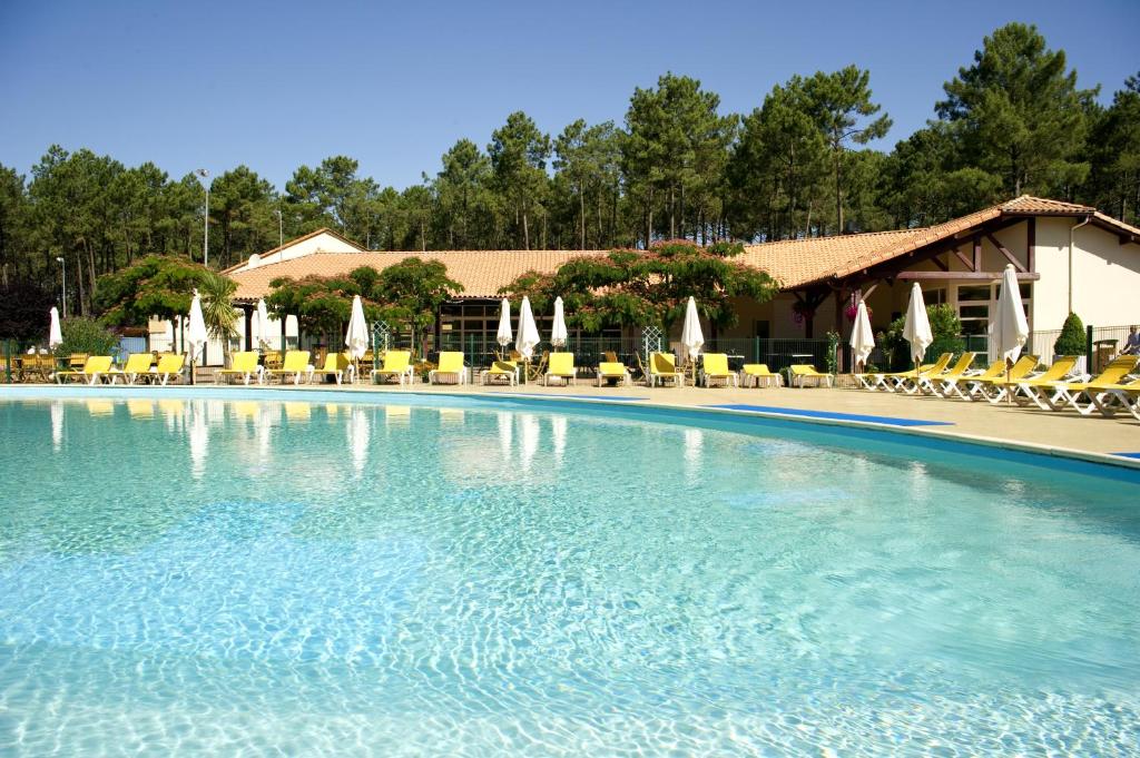 a large swimming pool with chairs and umbrellas at Village Vacances Le Lac Marin in Soustons