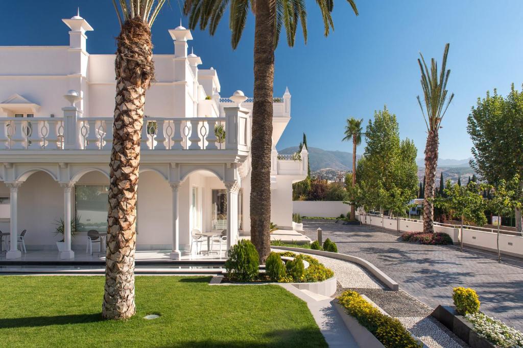 uma grande mansão branca com palmeiras num quintal em Quinta Real Granada em Huétor Vega
