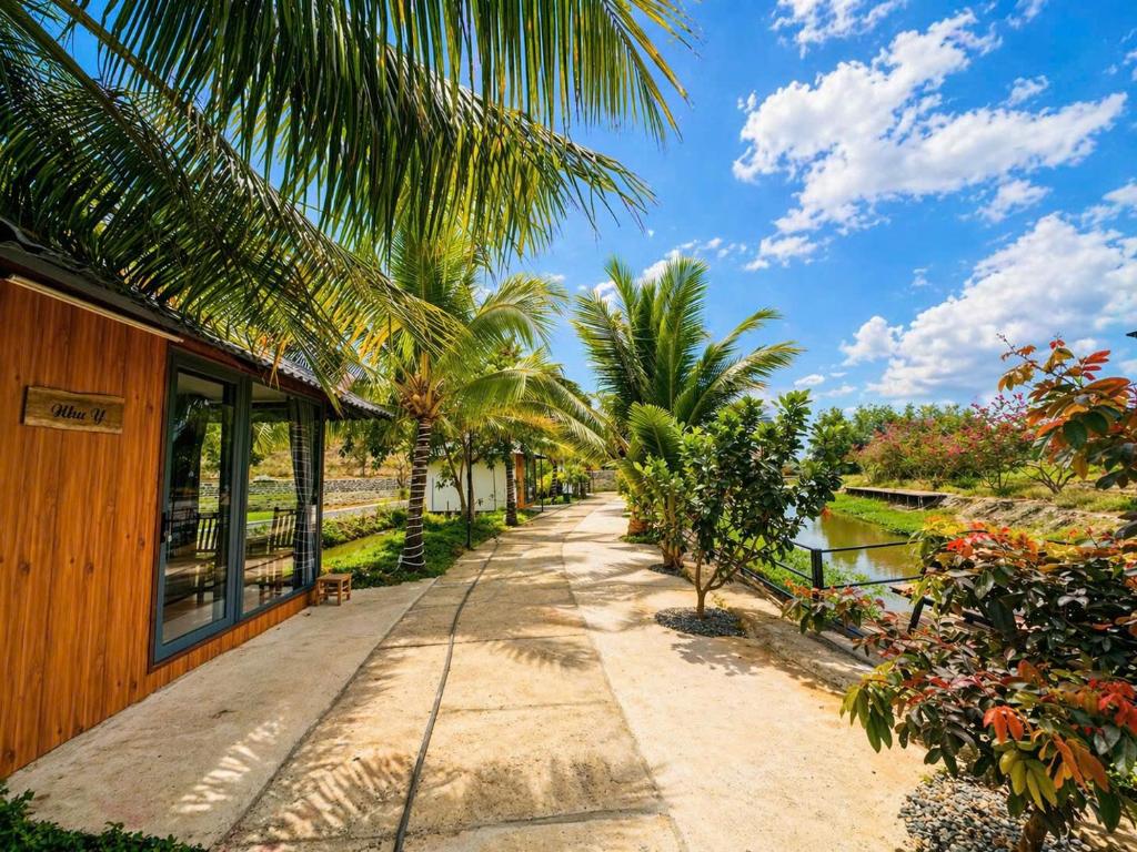 a path next to a house with palm trees at LUA Farmstay in Bà Rịa