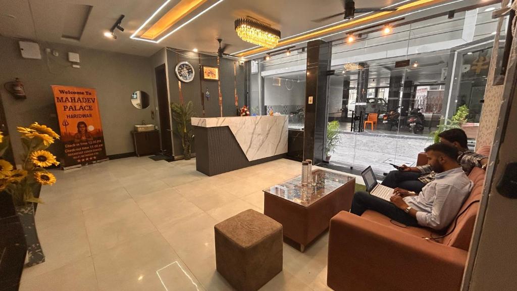 two people sitting in chairs in a store lobby at Hotel Mahadev Palace in Kankhal