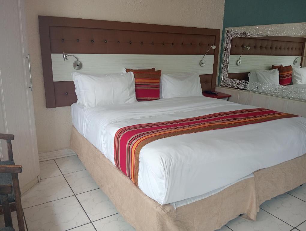 a bedroom with a large bed with a large white comforter at Steps On Cape Guest House in Gqeberha