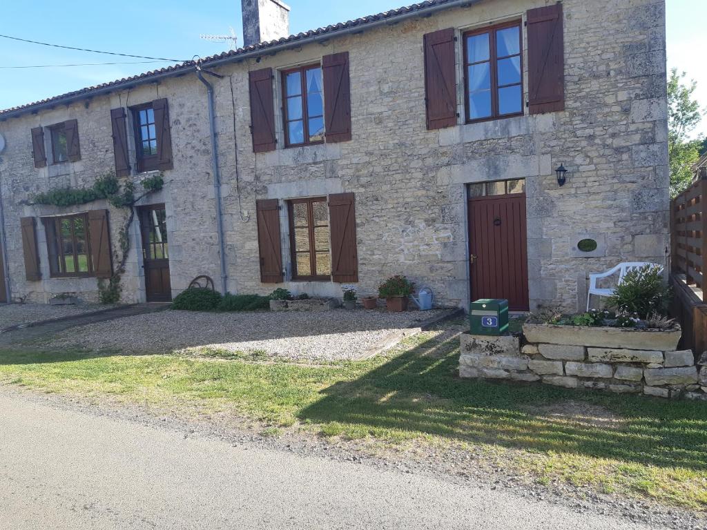 a stone house with brown shutters and a driveway at The Old Forge in La Ressière