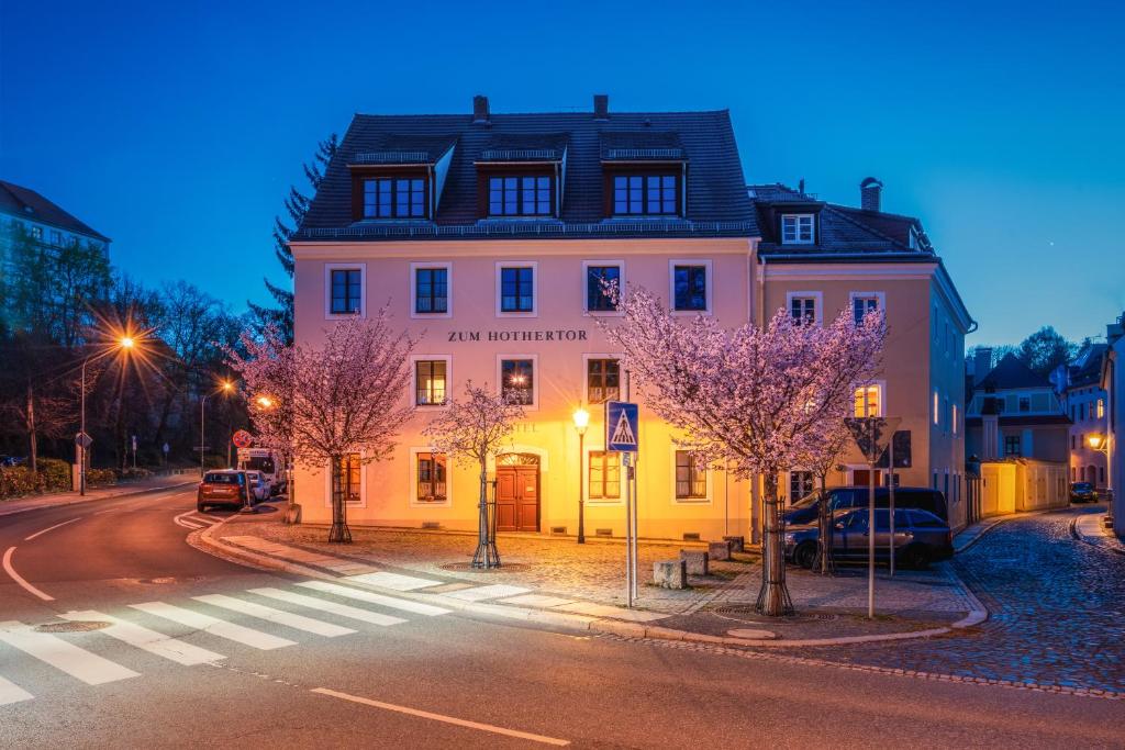 a building on the side of a street with trees at Garni Hotel Zum Hothertor in Görlitz
