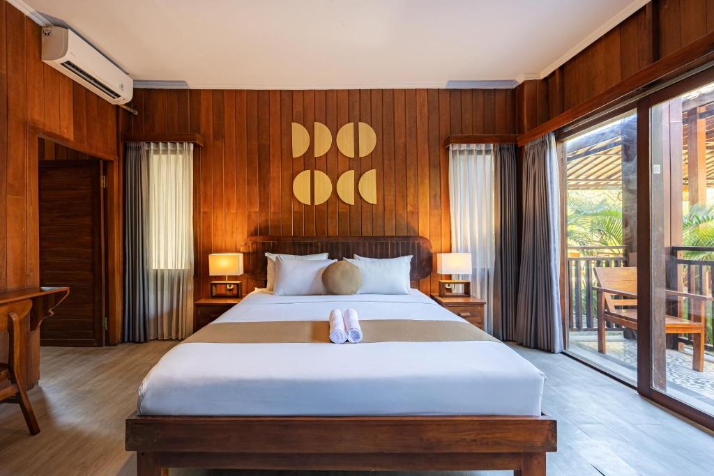 a bedroom with a large bed with wooden walls at Cove Dadeka in Canggu