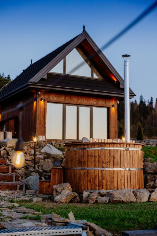 a log cabin with a porch and some rocks at Na Gorczańskim Wierchu Chalet, basen, sauna, balia na wyłączność in Rabka-Zdrój