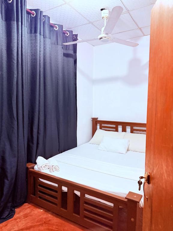 a bedroom with a bed with blue curtains at Ela addara Home stay in Lukasgoda