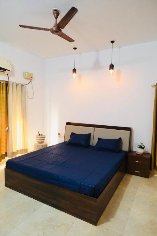 a bedroom with a blue bed with a ceiling fan at Peaceful Hideaway Ponda in Priol