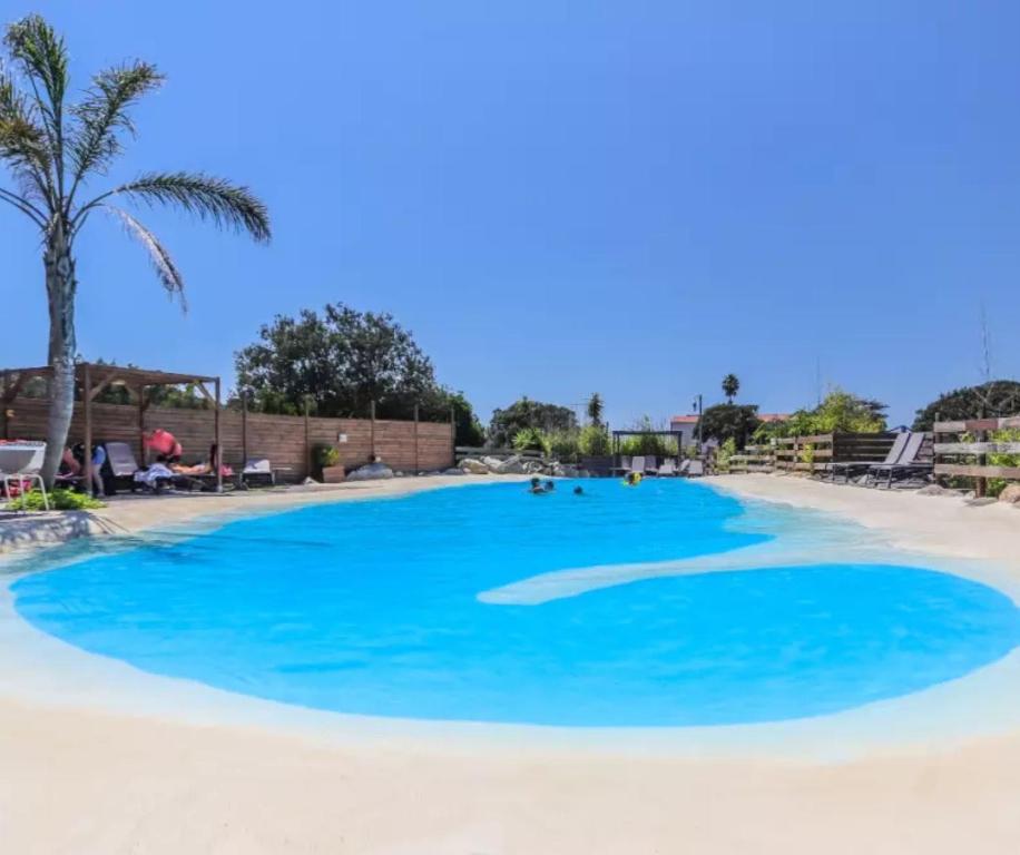 a large swimming pool with blue water on a beach at Cottage PARKS ESCAPADE COLOMBA in Olmeto