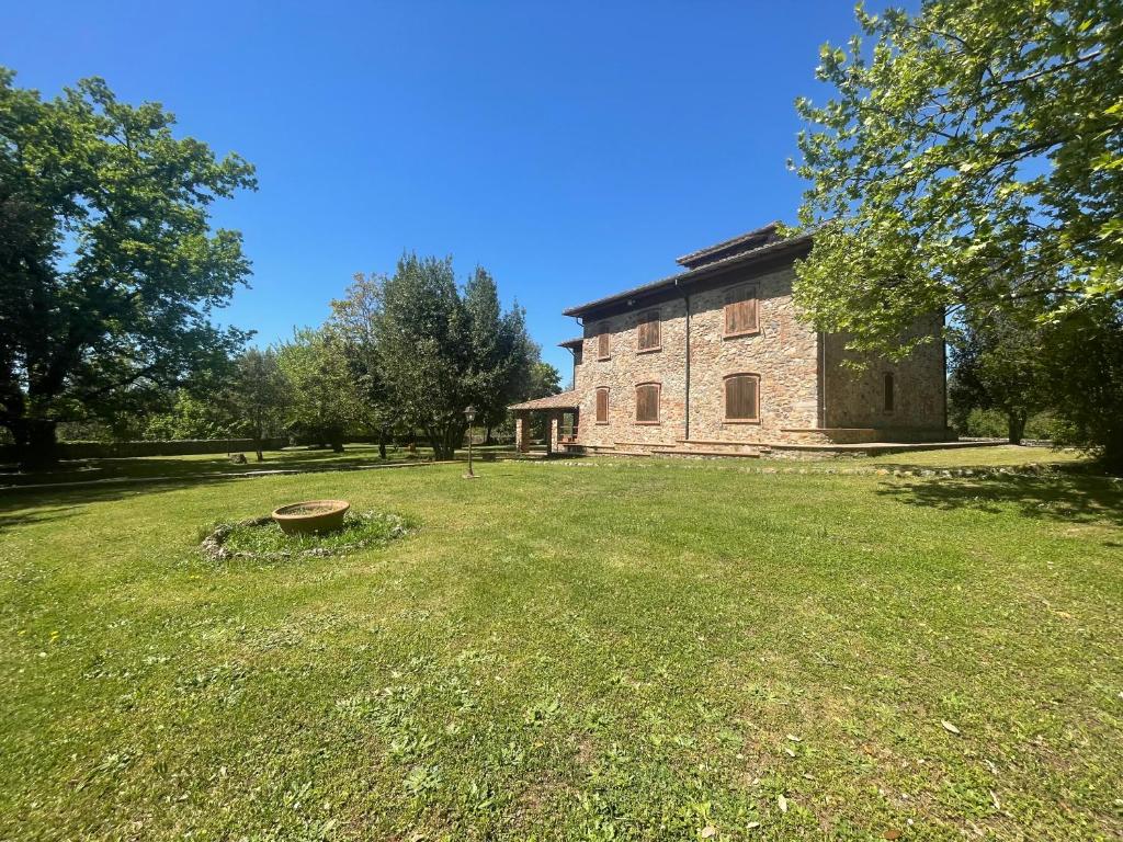 an old stone building in a field with a yard at Casabei in Monticiano
